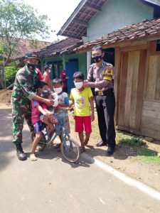 Sayang Anak Anak, Bhabinkamtibmas Bersama Babinsa Bagikan Masker Pada Anak Anak